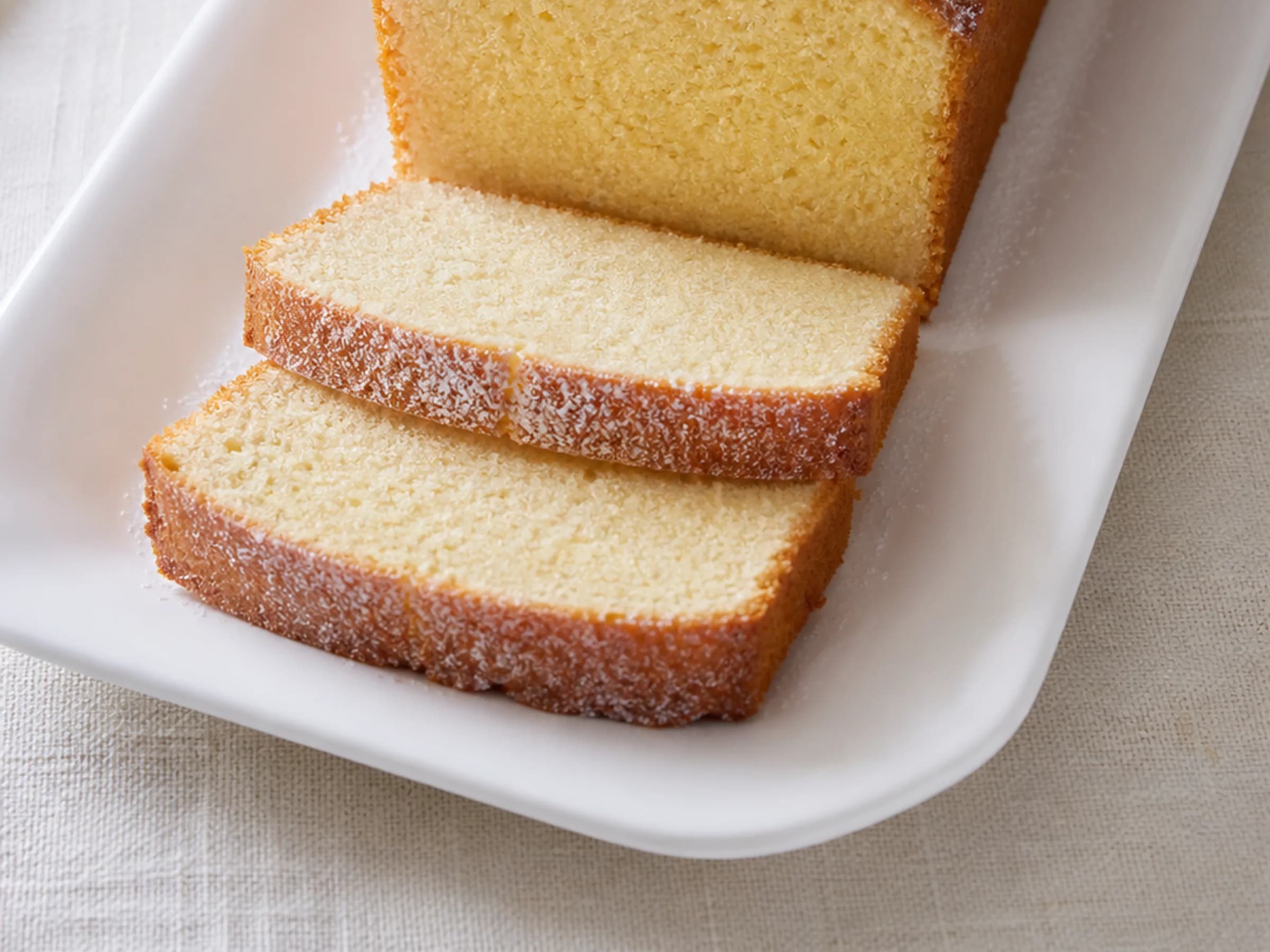 Aufgeschnittener Sandkuchen aus der Kastenform mit Puderzucker und feiner goldgelber Krume