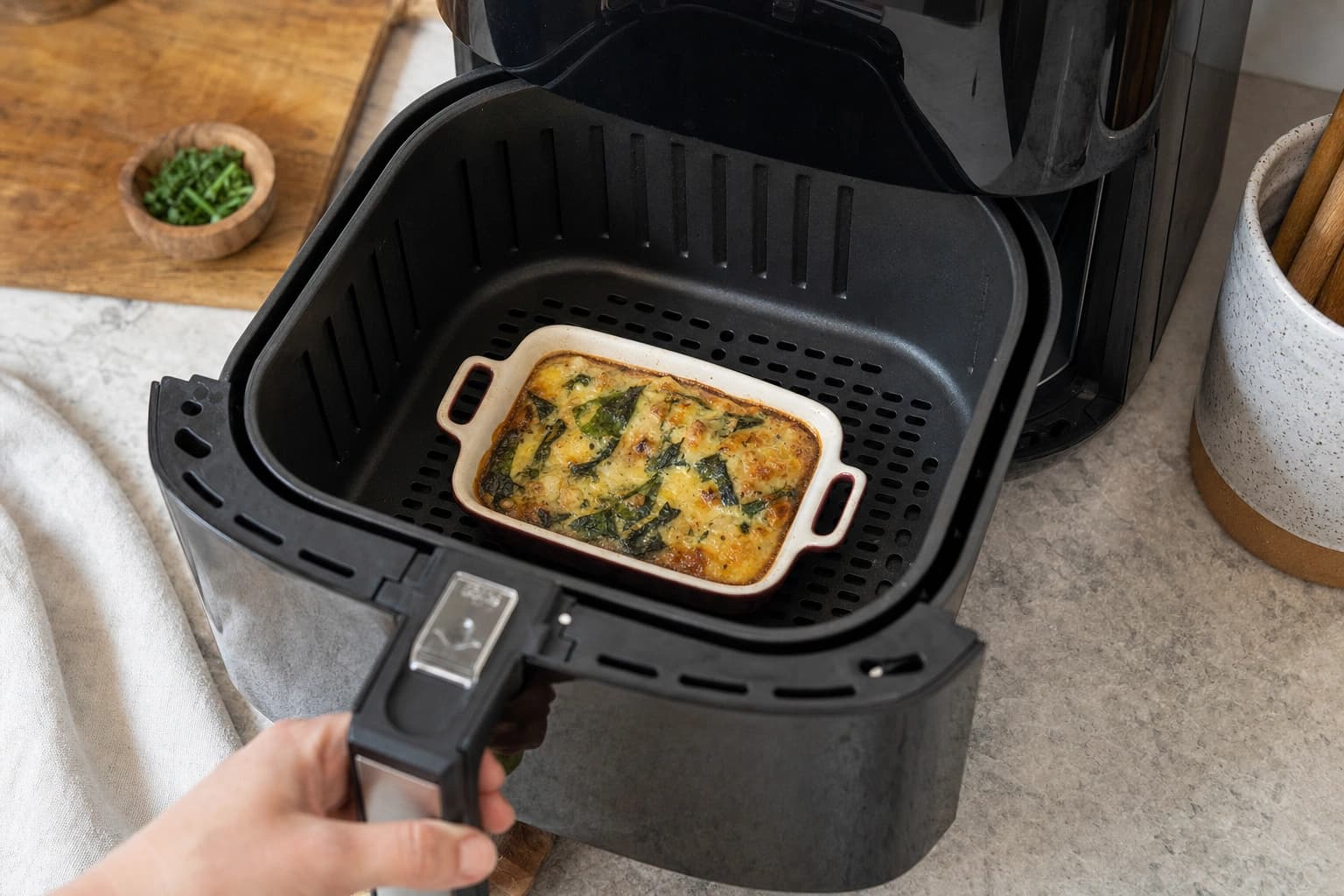 Eine kleine ofenfeste Form wird mit Luft rundherum in einen Airfryer-Korb eingesetzt.
