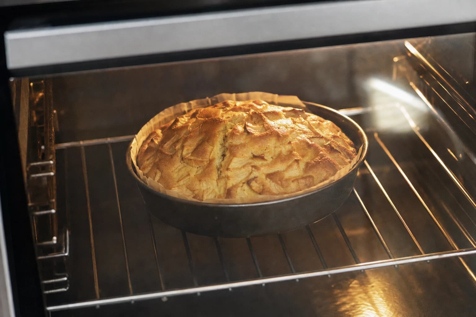 Ein ungleichmäßig aufgegangener Apfelkuchen mit natürlichem Riss backt allein in einer gebrauchten Springform.