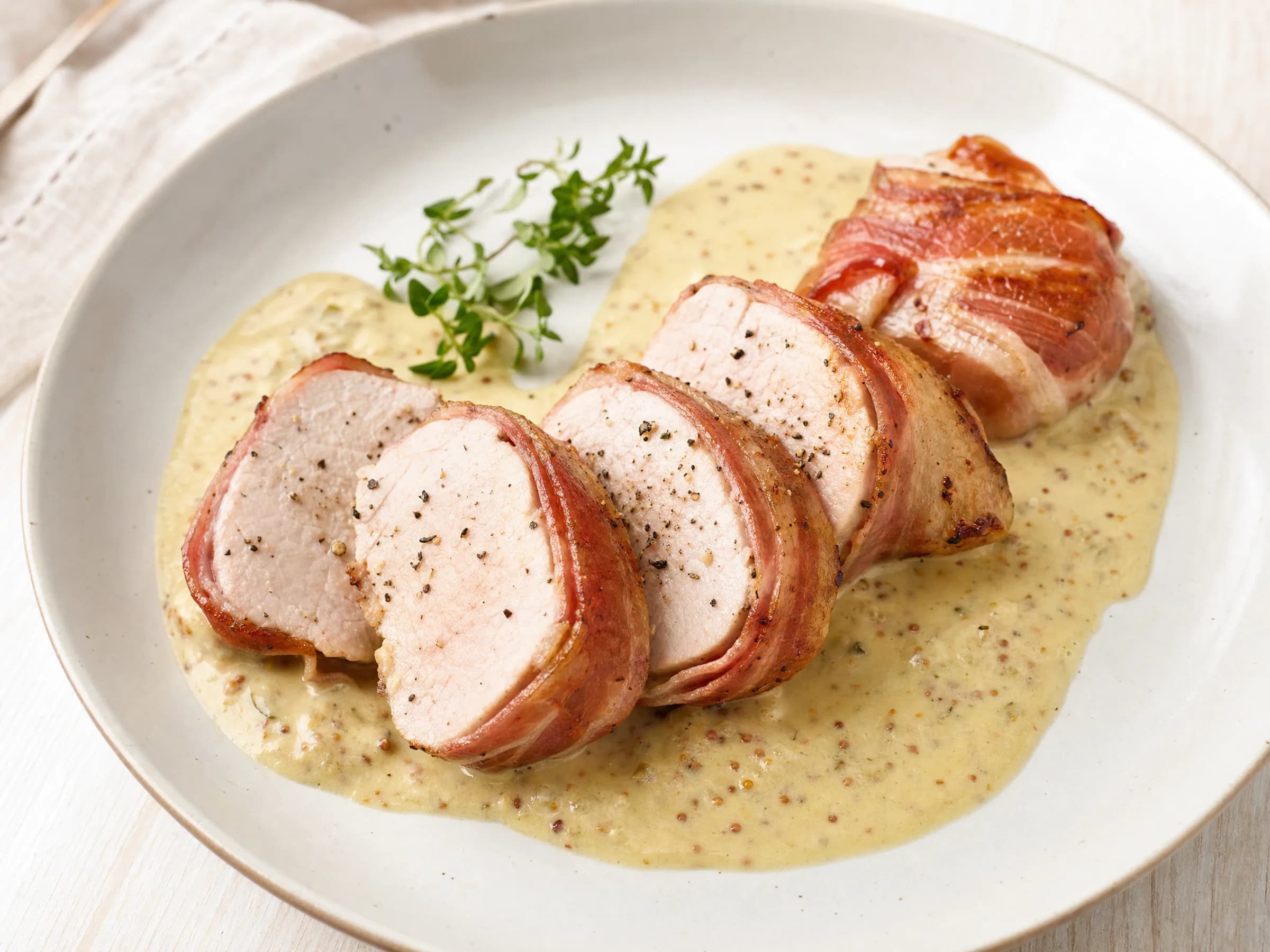 Schweinefilet im Speckmantel mit Senf-Sahne-Soße Rezeptfoto Schweinefilet im Speckmantel mit Senf-Sahne-Soße fertig angerichtet